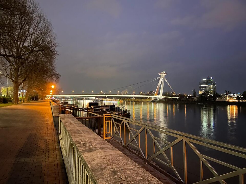 Le pont SNP et sa tour-restaurant illuminés la nuit, reflétés dans le Danube.